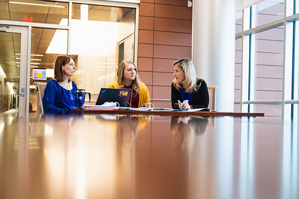 a student sitting at a table with two professionals having a conversation