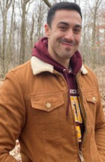 Ty Stebelton, Supplemental Instruction Leader at CMU, stands outdoors in autumn wearing a maroon hoodie and tan coat.