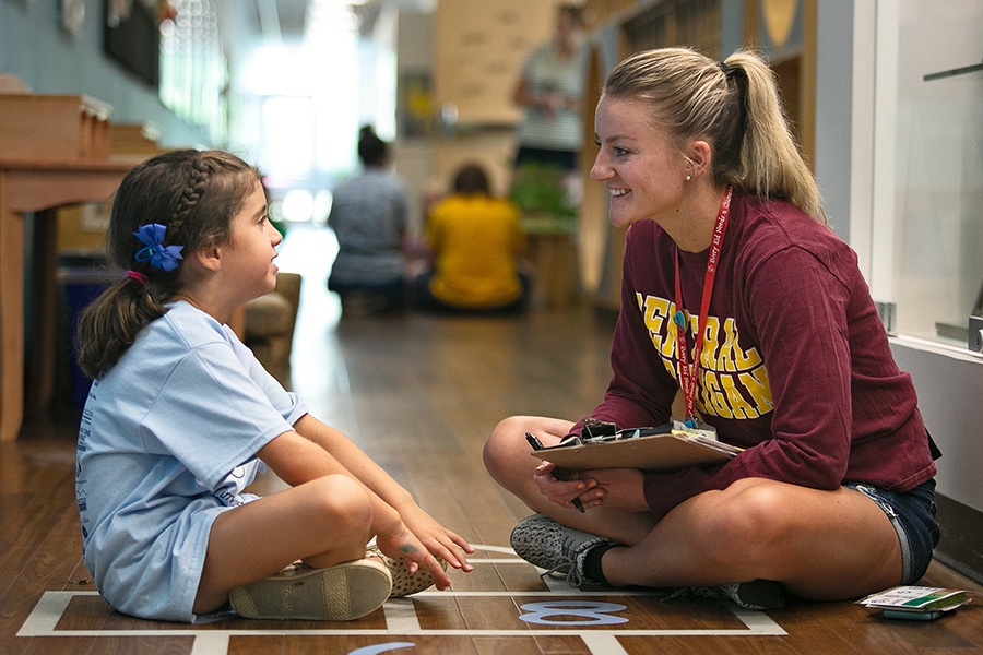 Central Michigan University student talking with a young child in a school setting