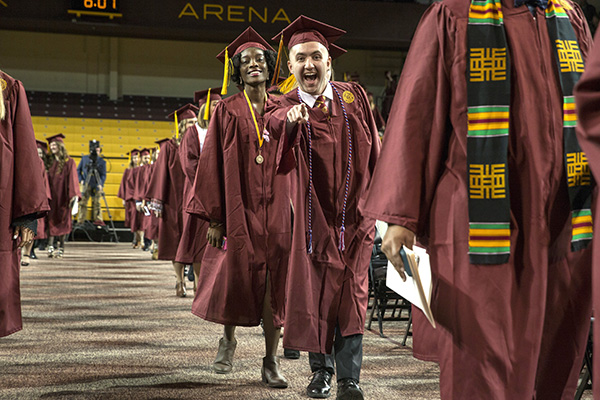 Happy Central Michigan graduate points directly at camera during commencement ceremony