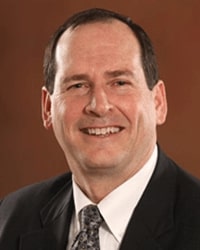 BillKanineFinal William (Bill) Kanine wearing a black suit with a gray tie and he has short dark brown hair.