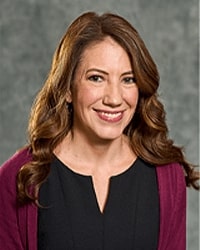 Alumni Board member Lisa Bottomley wearing a black top and a maroon cardigan and she has long brown hair.