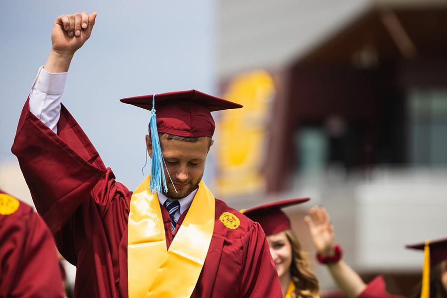 A new Central Michigan graduate raises his fist in pride at commencement ceremony
