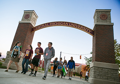 Students walking under the Central Michigan University arch.