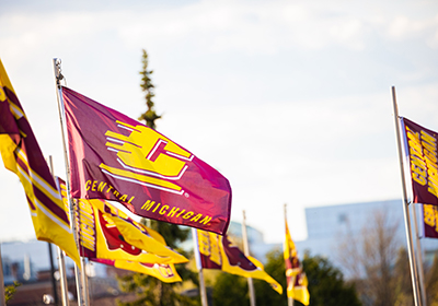 A bunch of Central Michigan University flags waving in the air.