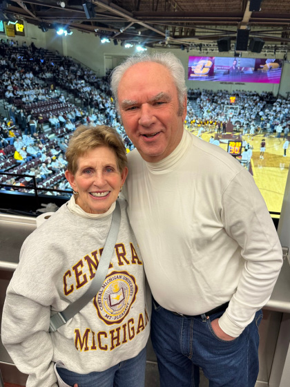 A man and woman pose for a picture inside a basketball arena.