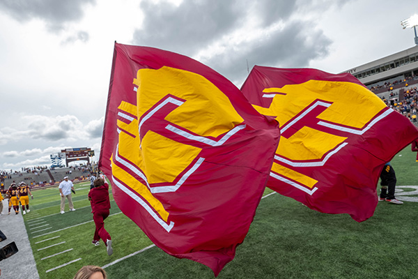 People running two large Central Michigan University flags down the football field.