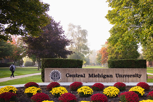 The concrete Central Michigan University sign with maroon and gold flowers in front of it.
