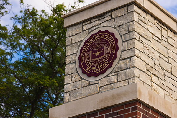The Central Michigan University seal on a brick pillar.