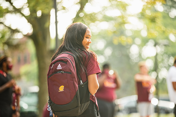 A student walking with a Central Michigan University backpack and smiling.