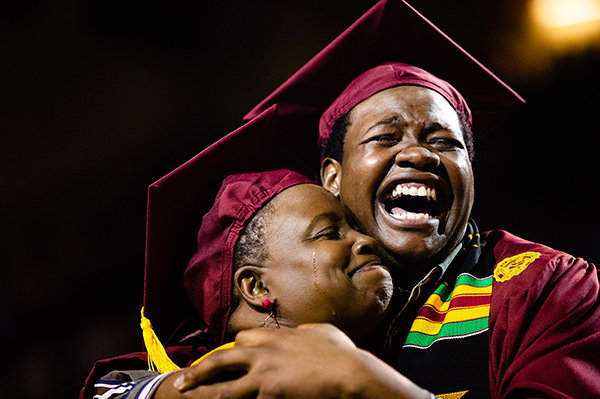Two graduates at graduation embracing each other.