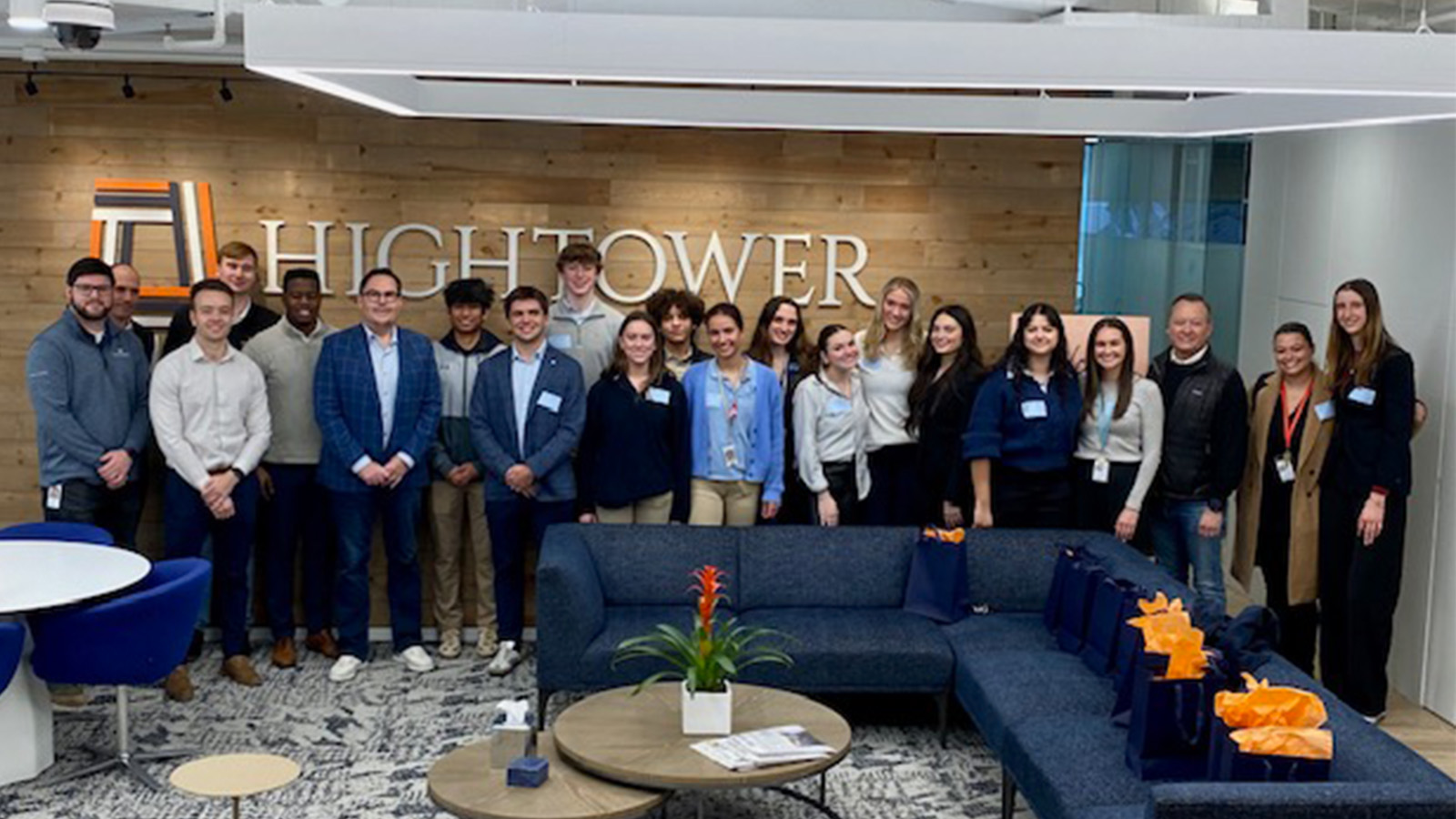 A group of 21 people pose for a photo inside a lobby with the word 