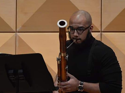A man plays a bassoon in the School of Music.