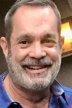 A profile image of a man with short hair and a grey beard smiling.