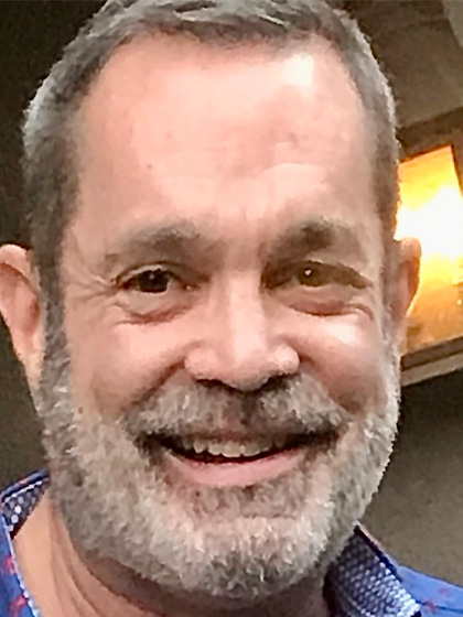 A profile image of a man with short hair and a grey beard smiling.