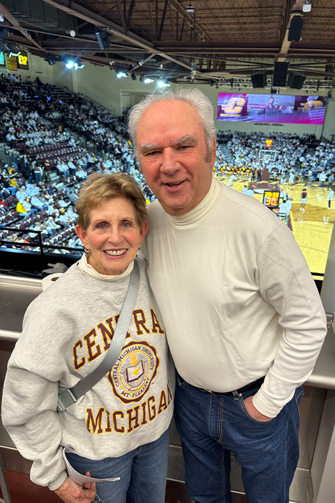 A man and woman pose for a picture inside a basketball arena.