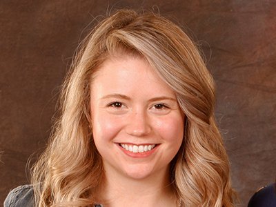 A women with blonde wavy hair smiles for the camera.