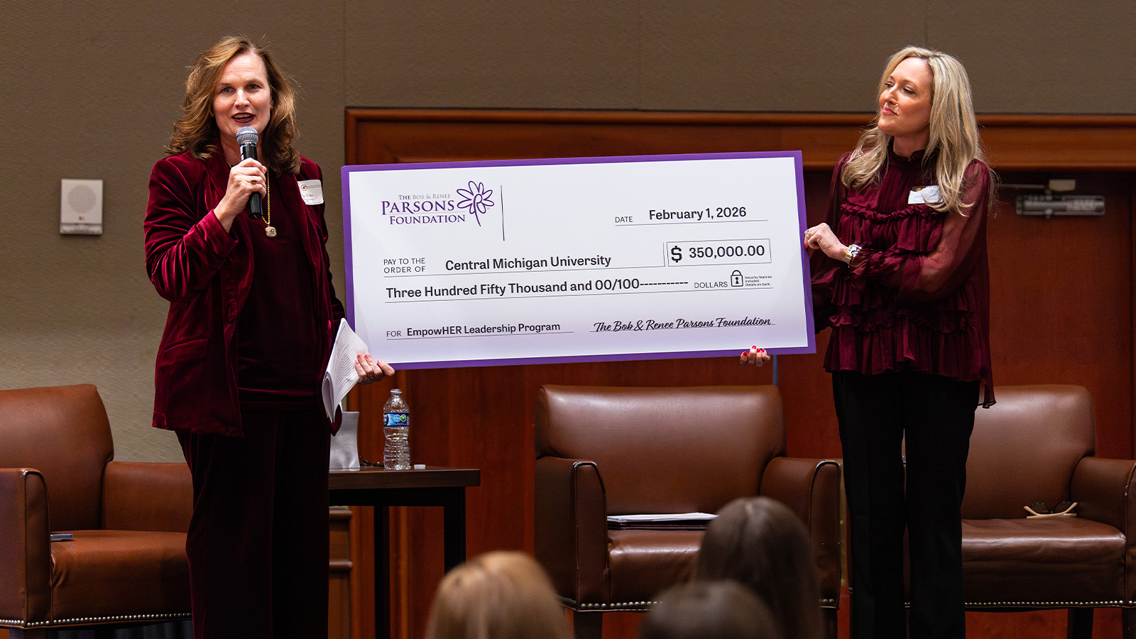 Two woman are holding a large check.