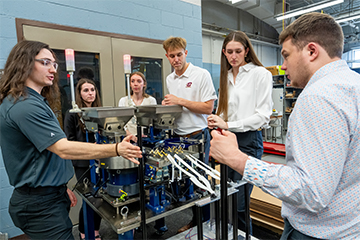 A group of people stand around a transmission machine.