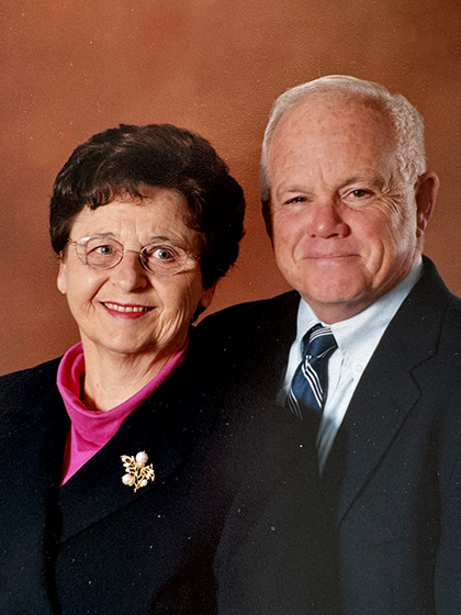 A close-up portrait of a married couple wearing business attire.