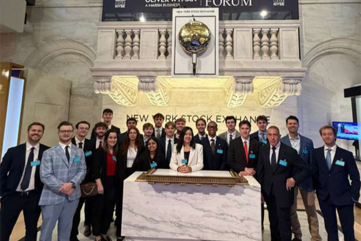 A group of people standing in front of a podium inside the New York Stock Exchange.
