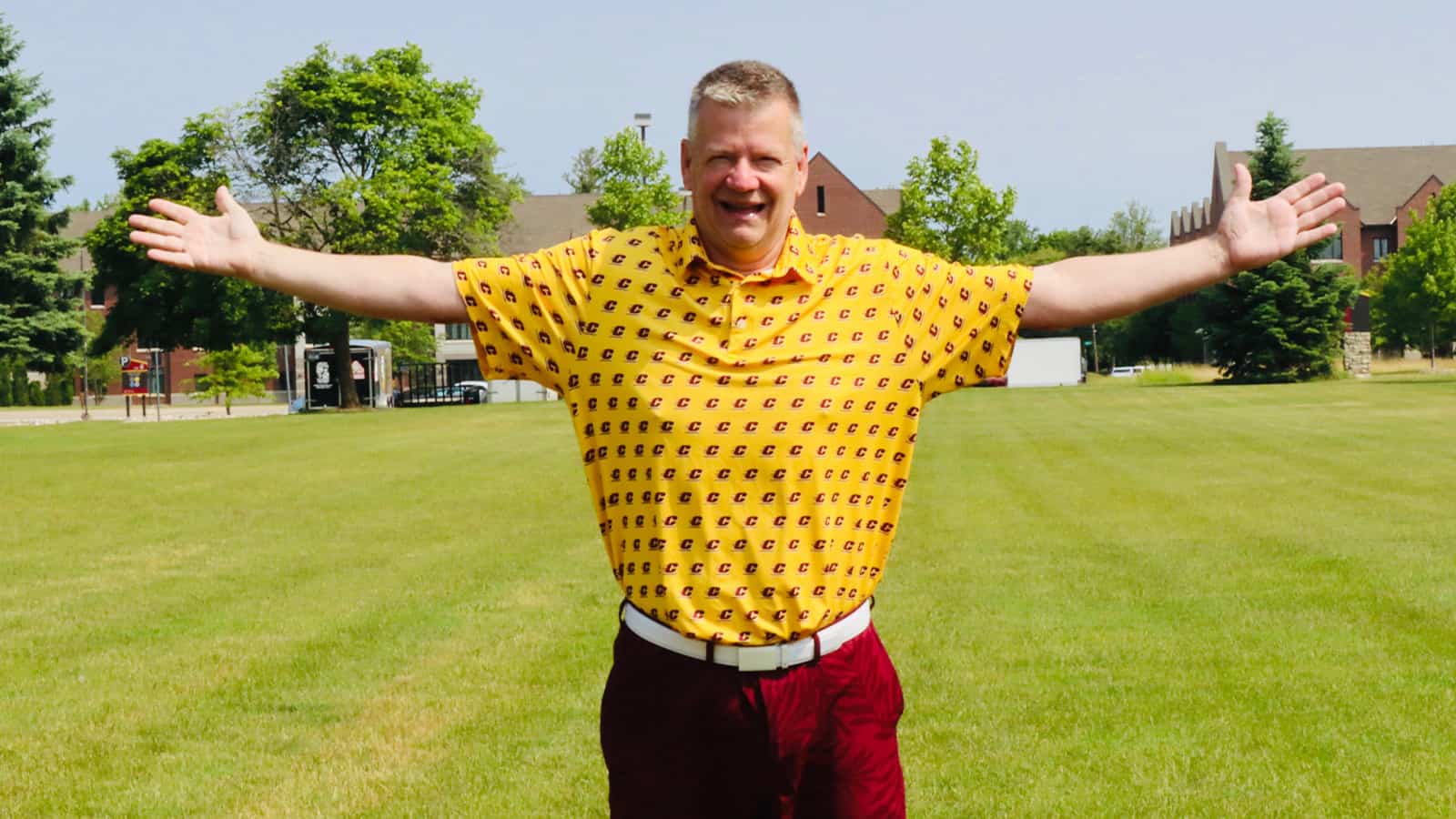 TO 1600x900 for TO story A man wearing a yellow polo and maroon shorts stands with his arms spread out.