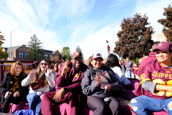 Central Michigan University alumni board members dressed in maroon and gold on a float during the CMU homecoming parade.