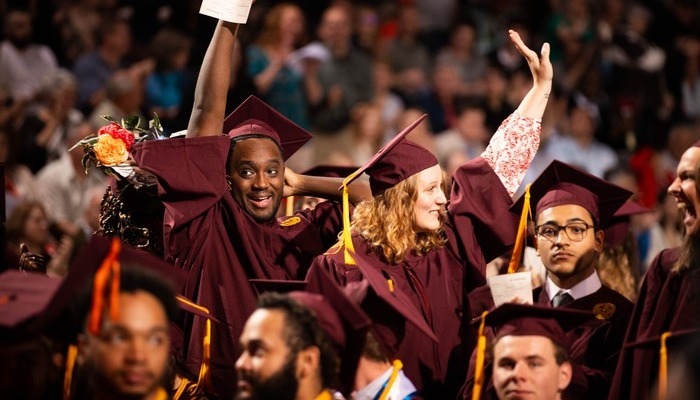 alumni_connect_commencement_700x400 Group of CMU graduates in maroon caps and gowns raising hands in celebration at a commencement ceremony.