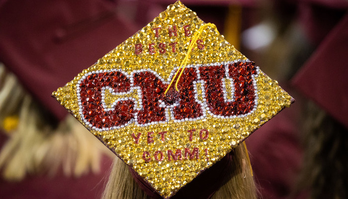 alumni_gold_benefits_700x400 A CMU graduate wearing a decorated graduation cap with sparkling letters and text saying 'The Best Is Yet to Comm!' and 'CMU'.