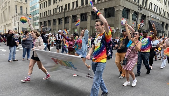 alumni_LGBTQIA_700x400 Members of CMU's LGBTQIA+ community walk in parade while holding a pride sign and flags.