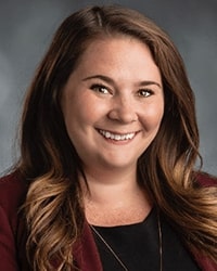 Professional headshot photo of Megan Blue smiling in front of a gray backdrop.