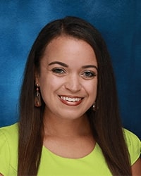 This is a headshot of Dana Whyte wearing earrings and a green top.