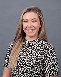 Headshot of 2024 Alumni Awards 10 Within 10 Recipient Monica Bradburn wearing a leopard print top and she has long blonde hair and is smiling with teeth.