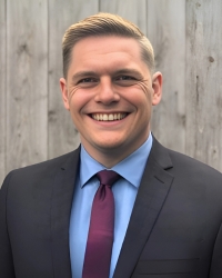 a man in a gray suit smiling outdoors