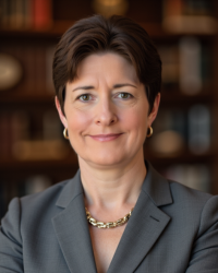 Amy Thompson 200x250 A woman with short dark hair wearing a suit and gold necklace.