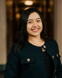 Carolina Hernandez Ruiz 200x250 A woman with dark hair and a dark suit smiling at camera.