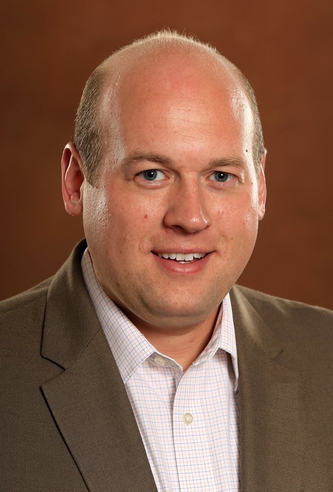 N Tallman Headshot a man in a brown suit