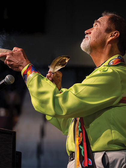 A man in a lime green shirt holding a feather and a bowl.