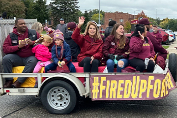 CMU Alumni Board and family members ride on a float and wave during the Homecoming Parade.
