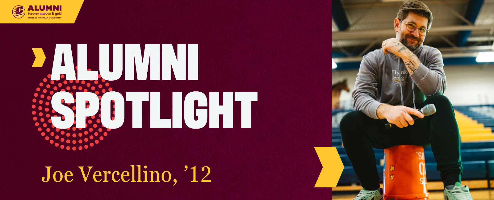 JoeVercellino_header_1600x650 Central Michigan University Alumni Spotlight graphic featuring Joe Vercellino, class of 2012, wearing a grey hoodie and holding a microphone while sitting on an orange bucket in a gymnasium.
