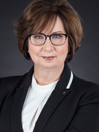 Julie is wearing glasses with black and white professional clothing.
