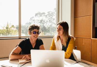 An alumna with a current student viewing a laptop screen together.