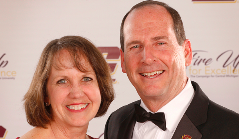 Bill and Carla Kanine dressed professionally in front of a CMU photo backdrop.