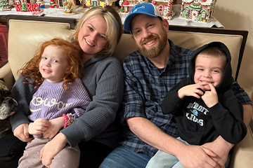 a man and woman sitting on a couch with two children and a dog