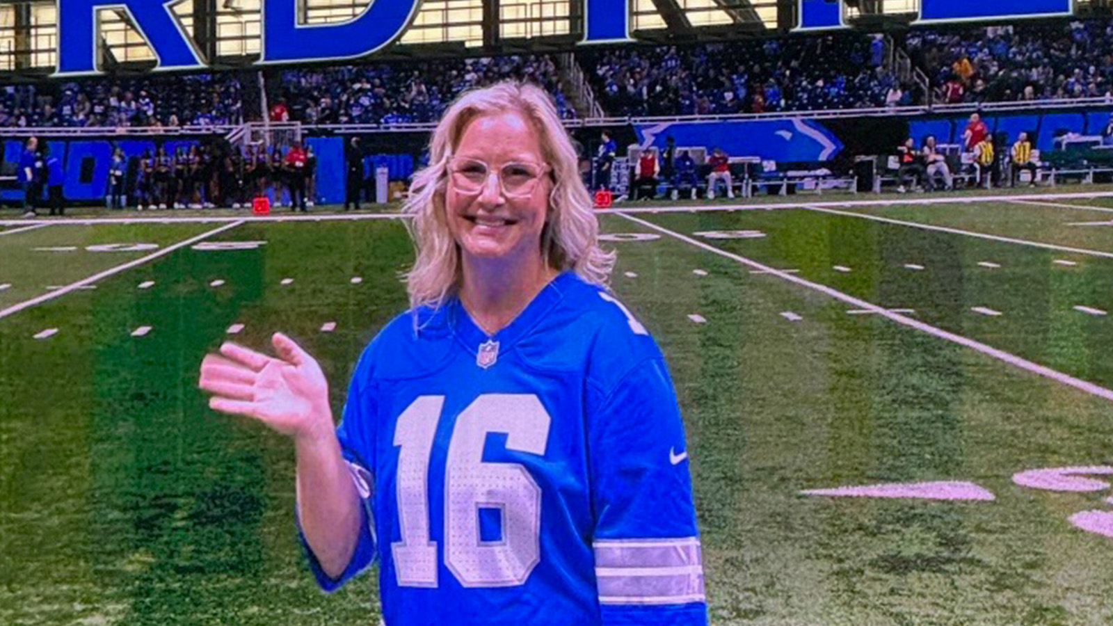 A woman in a blue jersey stands on a football field.