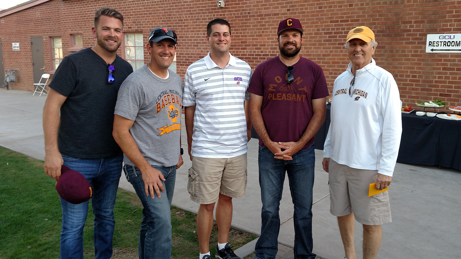 A group of five men standing together outside.