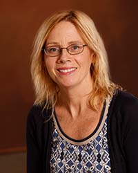 Michelle Bigard Michelle Bigard wears glasses, a dark sweater and patterned blouse in a professional headshot.