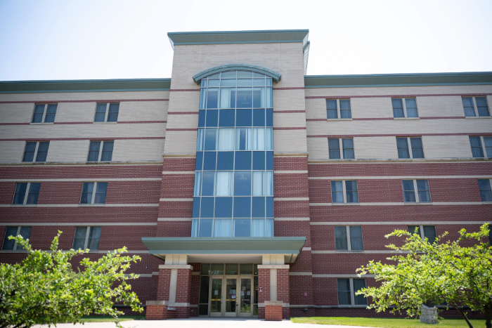 Front view of Campbell Hall, a five-story residence hall with a central glass tower and brick facade.