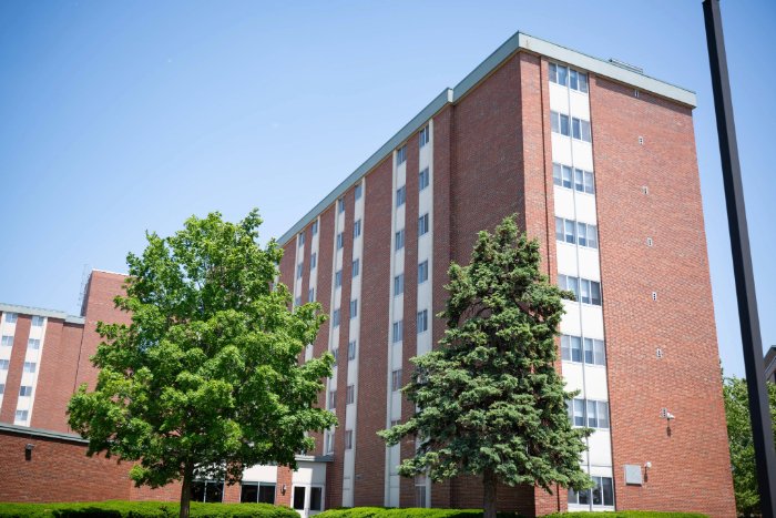 Carey Hall sign in front of a tall red brick residence hall.