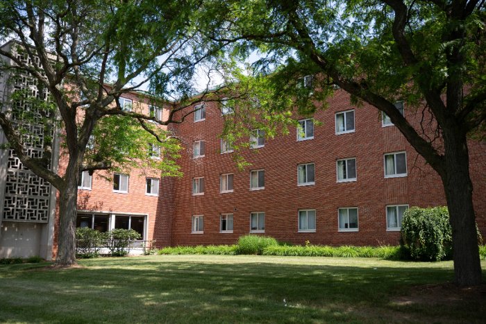 ThorpeHall700x467 Side view of Thorpe Hall with red brick walls, patterned concrete stairwell, and trees casting shade on the lawn.